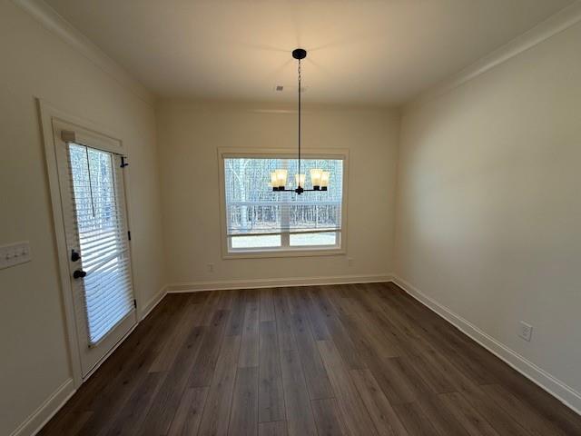 unfurnished dining area with a wealth of natural light, dark wood-style flooring, a notable chandelier, and baseboards