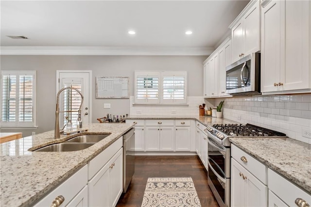 kitchen featuring white cabinetry, appliances with stainless steel finishes, sink, and light stone counters