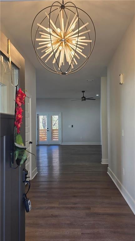 unfurnished living room featuring french doors, dark wood-type flooring, and ceiling fan with notable chandelier