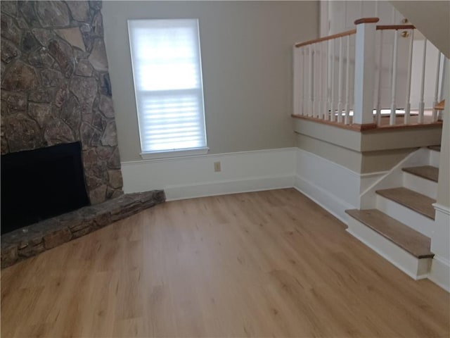 unfurnished living room featuring a stone fireplace and light hardwood / wood-style flooring