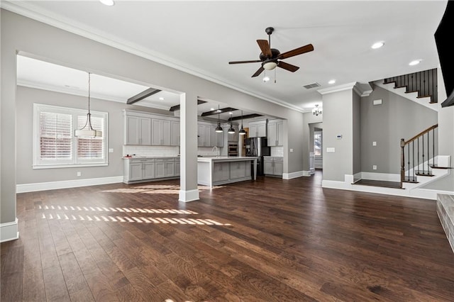 unfurnished living room featuring beam ceiling, dark hardwood / wood-style flooring, ceiling fan, and crown molding