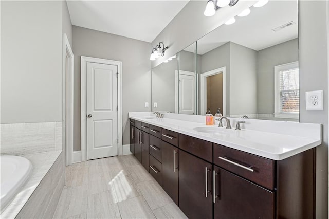 bathroom with tiled bath and vanity