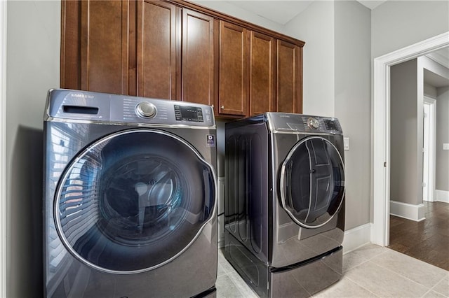 washroom with cabinets, light tile patterned floors, and washing machine and clothes dryer