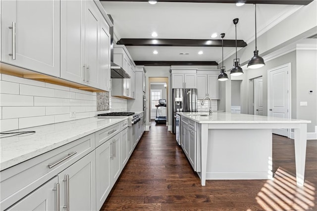 kitchen featuring backsplash, ventilation hood, decorative light fixtures, stainless steel gas stovetop, and an island with sink