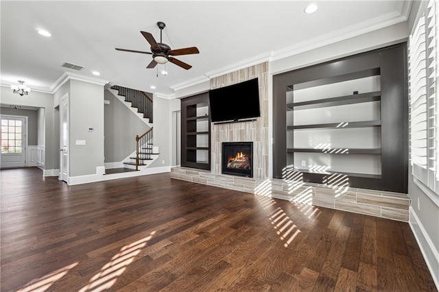 unfurnished living room with a large fireplace, ceiling fan, built in features, and ornamental molding