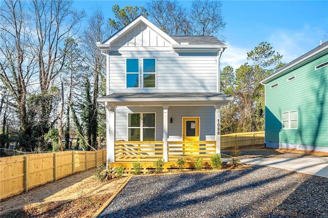 view of front of property featuring covered porch, board and batten siding, driveway, and fence