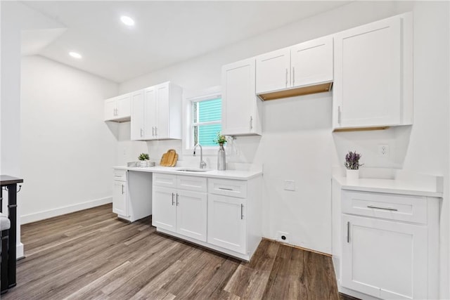 kitchen featuring white cabinets, wood finished floors, baseboards, and a sink