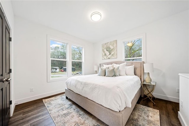 bedroom featuring multiple windows, baseboards, and dark wood-style flooring