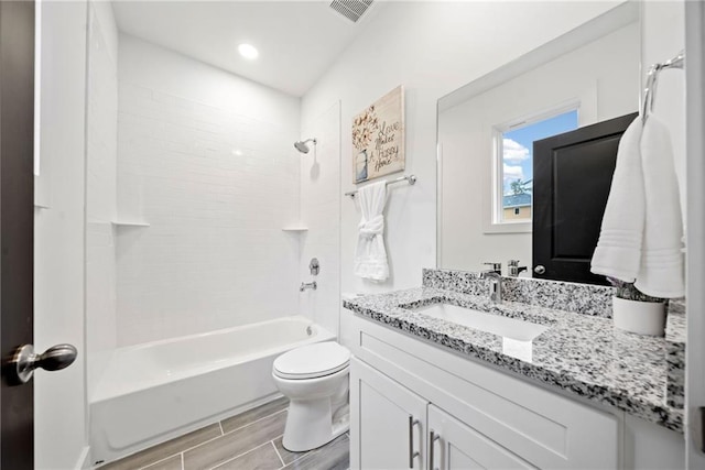 bathroom featuring vanity, visible vents, wood finish floors, shower / tub combination, and toilet