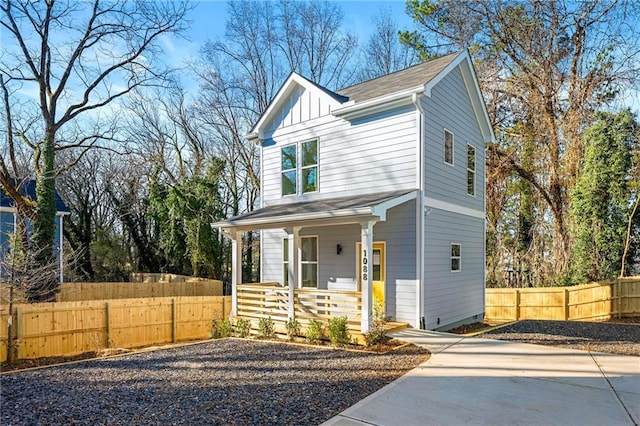 view of front of house with board and batten siding, covered porch, and fence