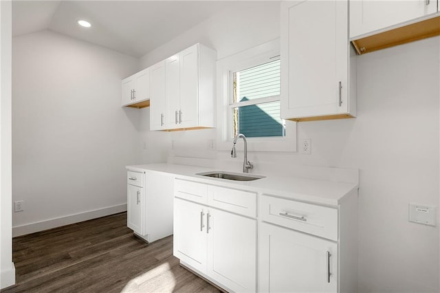 kitchen featuring dark wood-type flooring, a sink, white cabinets, light countertops, and baseboards