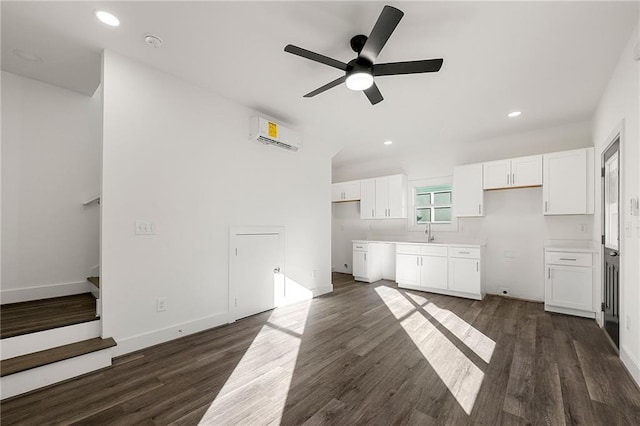 kitchen featuring white cabinets, dark wood-style floors, a wall mounted air conditioner, and a sink