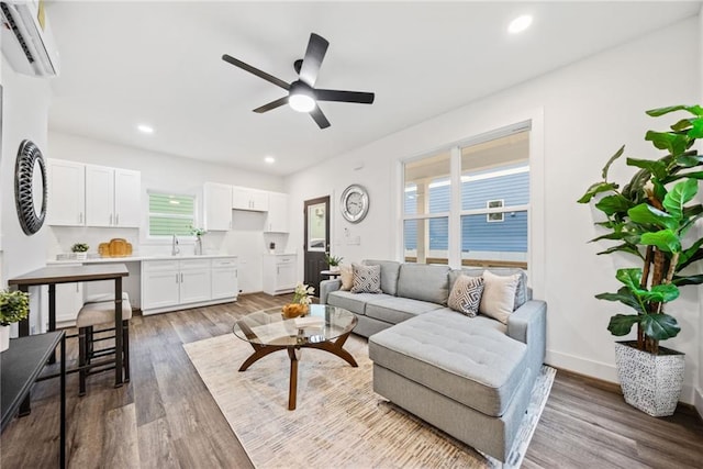 living area with a ceiling fan, recessed lighting, wood finished floors, and a wall mounted air conditioner