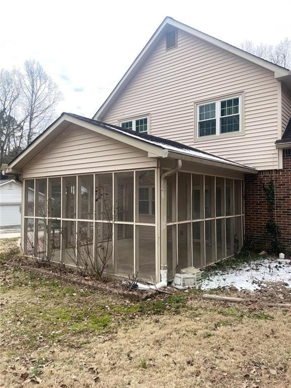 back of property with a yard and a sunroom