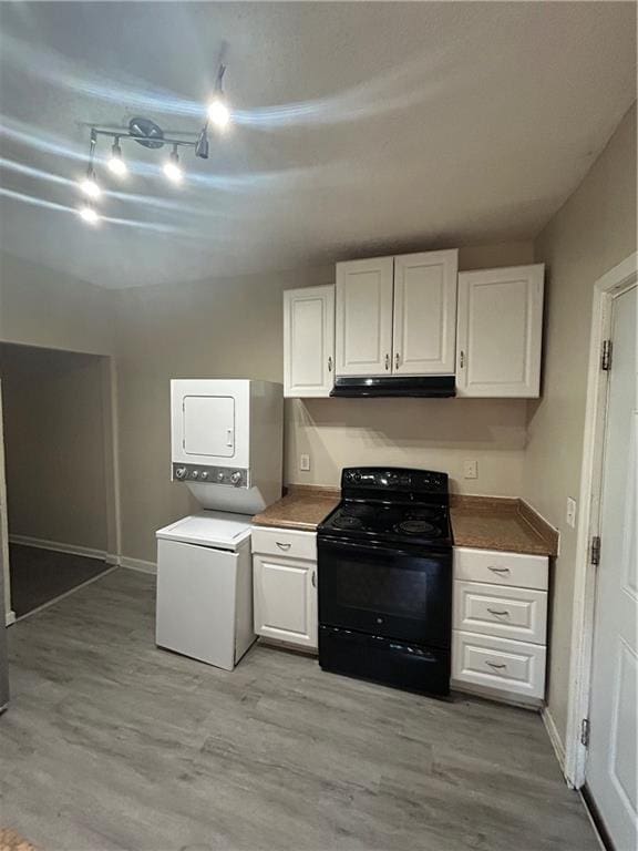 kitchen with black / electric stove, stacked washing maching and dryer, light hardwood / wood-style flooring, and white cabinets