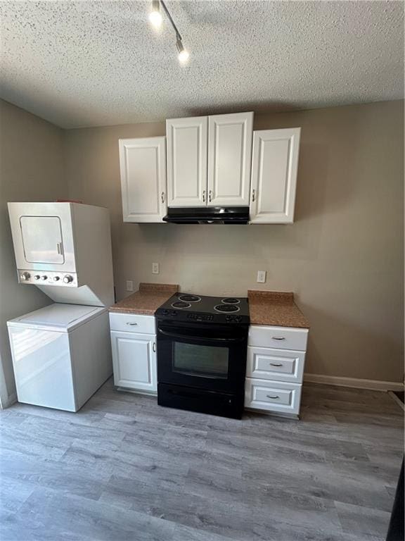 kitchen with light hardwood / wood-style floors, white cabinets, stacked washer / dryer, and black electric range