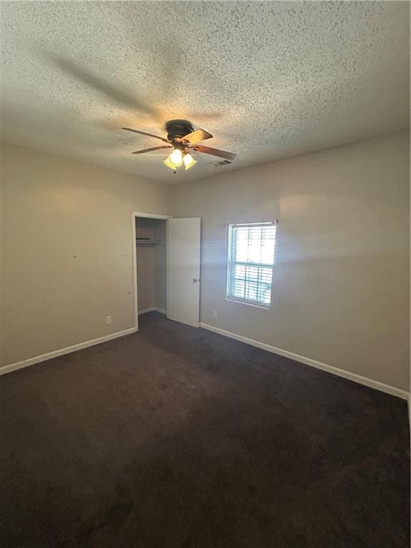 unfurnished bedroom with a closet, ceiling fan, a textured ceiling, and dark colored carpet