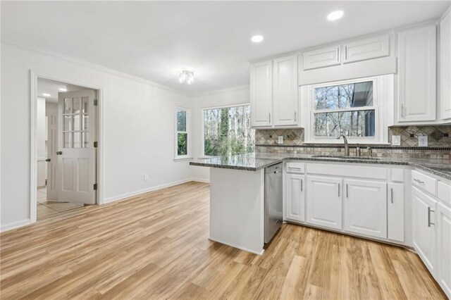 kitchen featuring stainless steel appliances, white cabinetry, dark stone countertops, and backsplash