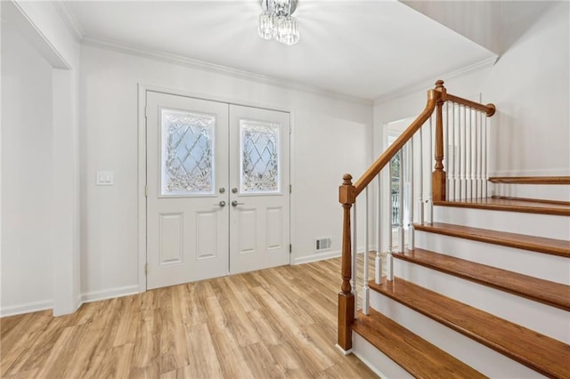 entrance foyer featuring a notable chandelier, ornamental molding, and light hardwood / wood-style flooring