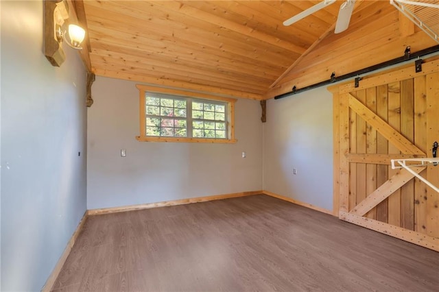 unfurnished room featuring vaulted ceiling, ceiling fan, a barn door, wooden ceiling, and hardwood / wood-style floors