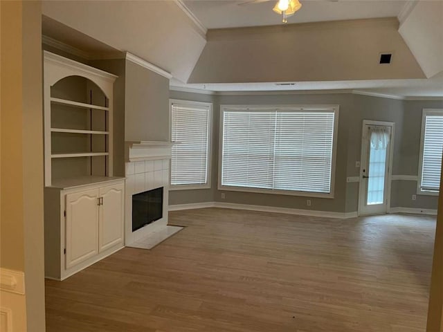 unfurnished living room with ceiling fan, a tile fireplace, lofted ceiling, and ornamental molding