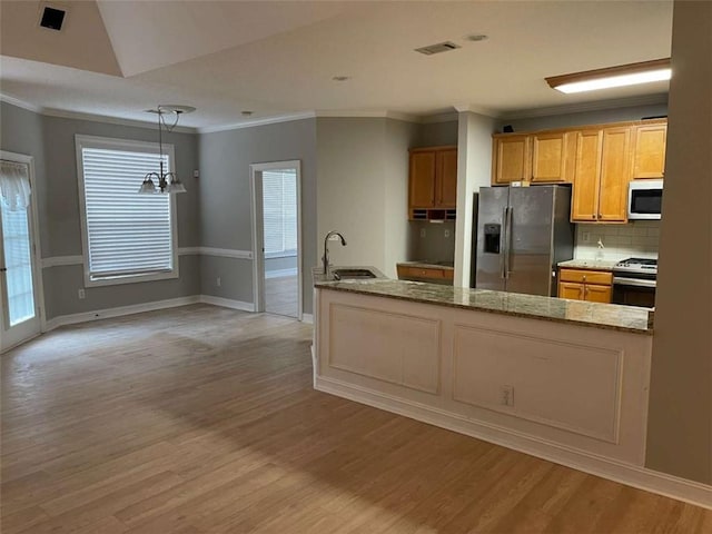 kitchen featuring pendant lighting, stainless steel appliances, tasteful backsplash, sink, and light hardwood / wood-style flooring