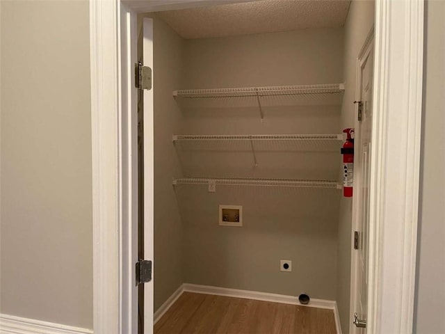 laundry room featuring a textured ceiling, hookup for an electric dryer, hardwood / wood-style flooring, and washer hookup