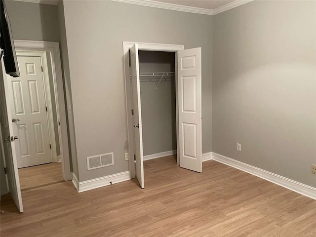 unfurnished bedroom featuring light hardwood / wood-style flooring, a closet, and ornamental molding