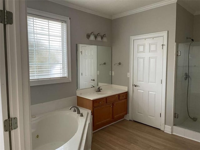 bathroom with wood-type flooring, vanity, crown molding, and shower with separate bathtub