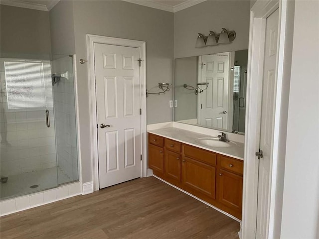 bathroom featuring ornamental molding, hardwood / wood-style flooring, walk in shower, and vanity