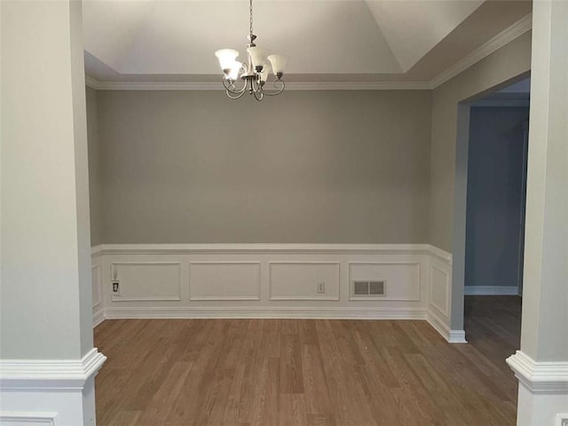 empty room with light hardwood / wood-style floors, ornamental molding, lofted ceiling, and an inviting chandelier