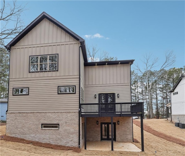 rear view of property featuring a wooden deck and a patio