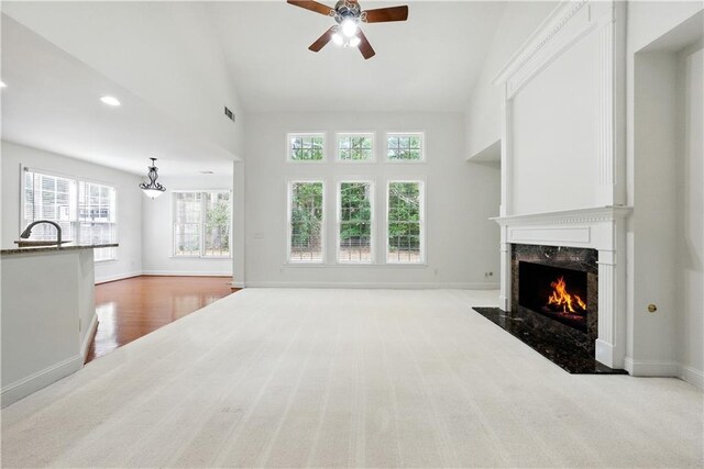 12554 Huntington Trce, Alpharetta, GA 30005 - unfurnished living room with a high end fireplace, a ceiling fan, vaulted ceiling, baseboards, and a sink