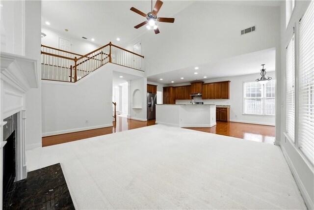 12554 Huntington Trce, Alpharetta, GA 30005 - unfurnished living room with a ceiling fan, a high ceiling, a fireplace with flush hearth, recessed lighting, and wood finished floors