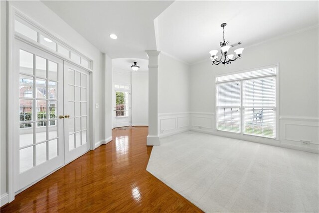 12554 Huntington Trce, Alpharetta, GA 30005 - empty room featuring decorative columns, crown molding, a chandelier, a wainscoted wall, and a decorative wall