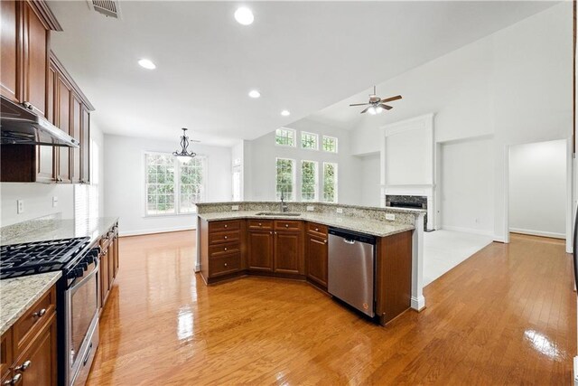 12554 Huntington Trce, Alpharetta, GA 30005 - kitchen featuring stainless steel appliances, ceiling fan, a sink, light wood finished floors, and a fireplace