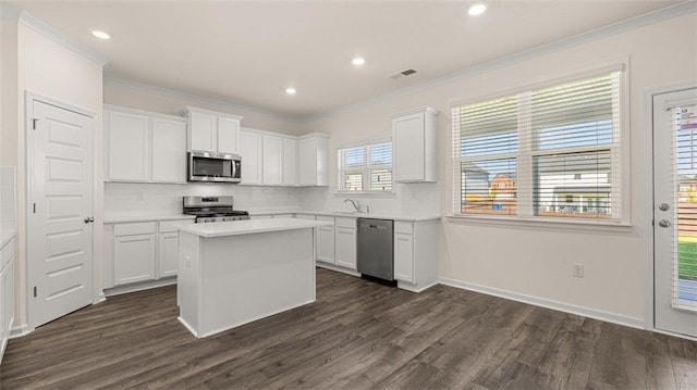 1149 Blue Juniper Cir, Loganville, GA 30052 - kitchen featuring appliances with stainless steel finishes, crown molding, dark wood-style flooring, white cabinets, and backsplash