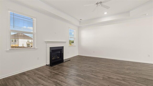 1149 Blue Juniper Cir, Loganville, GA 30052 - unfurnished living room featuring ornamental molding, dark wood-type flooring, a glass covered fireplace, a ceiling fan, and a raised ceiling