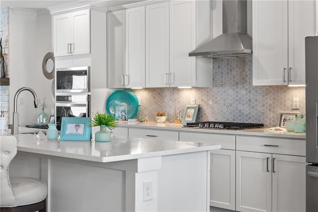 kitchen featuring light countertops, wall chimney range hood, and appliances with stainless steel finishes