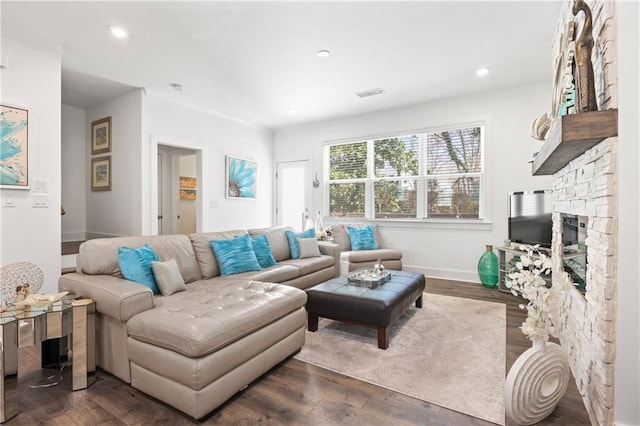 living room featuring visible vents, baseboards, dark wood finished floors, a stone fireplace, and recessed lighting