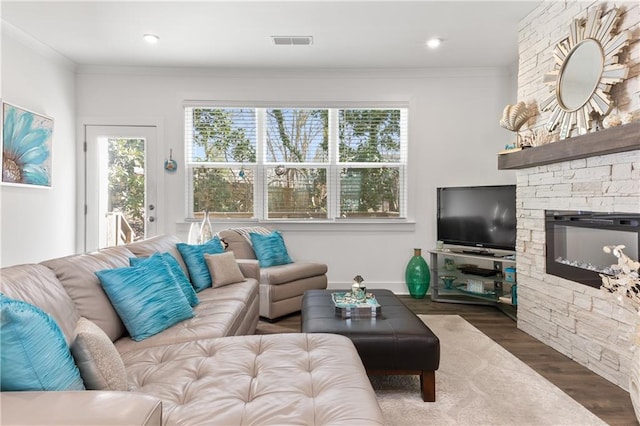 living room featuring visible vents, wood finished floors, a fireplace, and ornamental molding