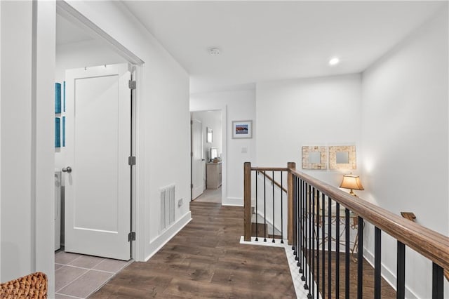 hallway with wood finished floors, visible vents, baseboards, recessed lighting, and an upstairs landing