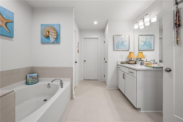 bathroom with vanity, a bath, and baseboards