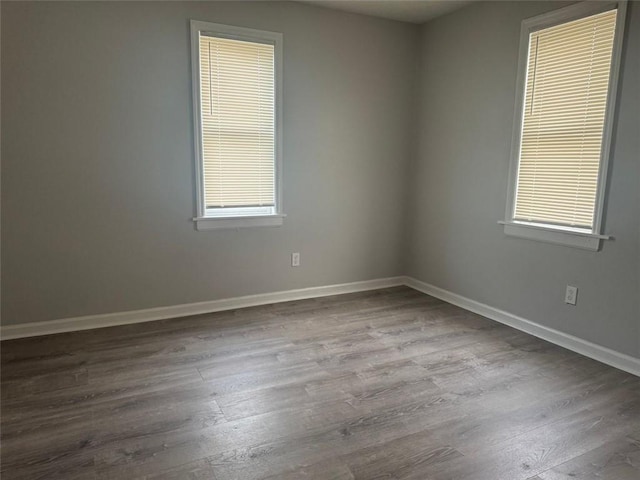 empty room with dark wood-type flooring, a healthy amount of sunlight, and baseboards