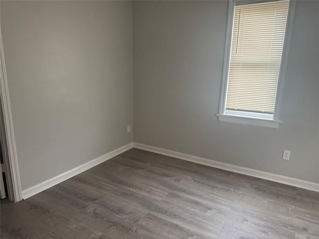 empty room featuring baseboards and dark wood-style flooring