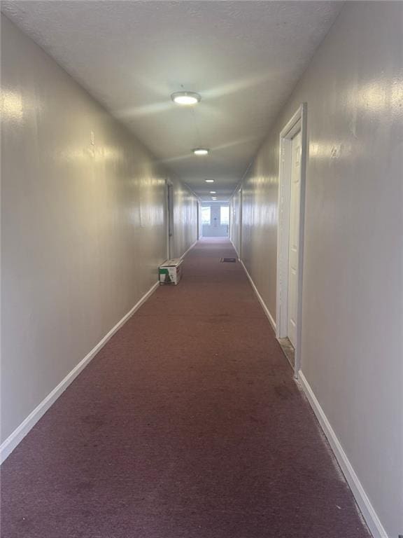 corridor featuring baseboards and carpet floors