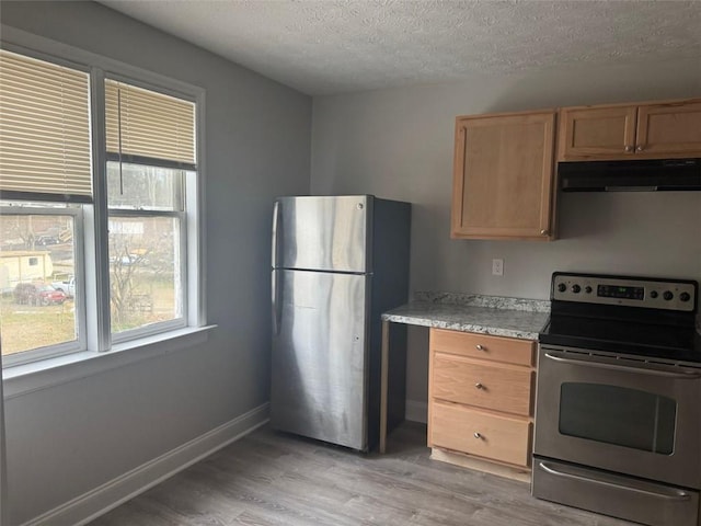 kitchen featuring light wood-type flooring, appliances with stainless steel finishes, exhaust hood, light countertops, and baseboards