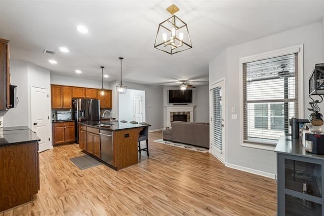 5925 Watersdown Way, Flowery Branch, GA 30542 - kitchen with a sink, dark countertops, a fireplace, appliances with stainless steel finishes, and light wood-style flooring