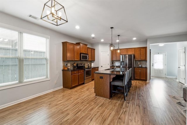 kitchen featuring brown cabinets, dark countertops, visible vents, a chandelier, and appliances with stainless steel finishes