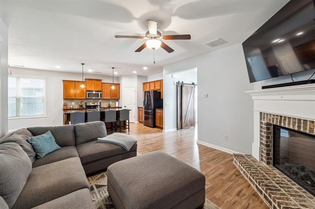 living room featuring recessed lighting, visible vents, light wood-type flooring, a fireplace, and ceiling fan